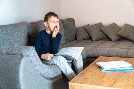 A yawning boy is bored studying at home. Self-study at homeの写真素材