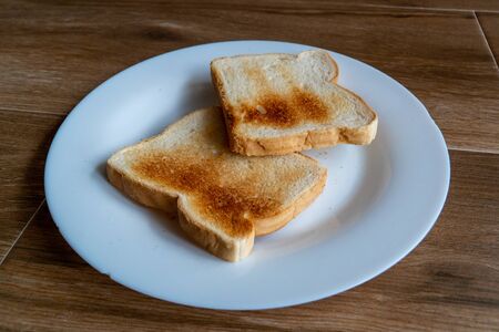 2 Slices of White Toasted Bread on White Plate. Cooking a delicious breakfast at home. Two pieces of...