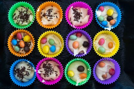 Homemade cupcakes in multi-colored silicone molds and with colored chocolates inside on a baking tray. Delicious pastry cooked at home. Homemade cakes for the familyの写真素材