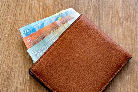 New leather wallet with euro money on a wooden background. Wallet wit a money.