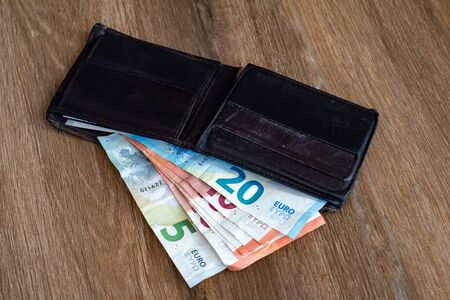 Old shabby wallet with euro money on a wooden background. Wallet wit a money. View from aboveの写真素材