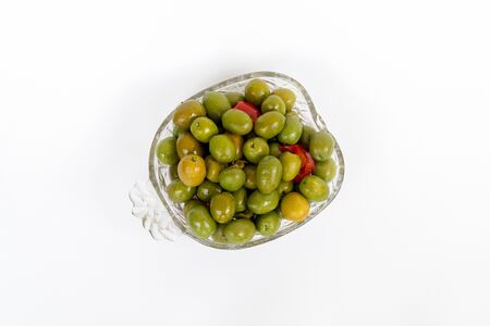 Pickled green olives with oregano, garlic, red pepper, herbs and spices. Marinated olives in transparent bowl. Pickled green olives. White background.の写真素材