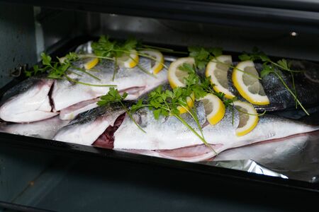 Fresh dorada fish with lemon and parsley on a baking sheet in the oven. Cooking fish at home