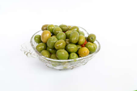 Recipe for marinated olives. Marinated olives in small transparent bowl. Pickled green olives. On white background. Pickled green olives with oregano, garlic, red pepper, herbs and spices.の写真素材
