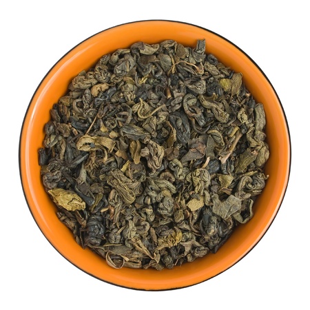 Dried green tea leaves in the orange cup. Isolated on a white background with paths.の写真素材