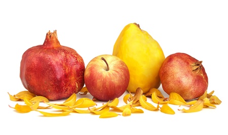 Dried pomegranates, apple, quince and leaves of pomegranate over a white background.の写真素材