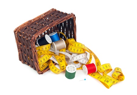 Box with measuring tapes and spools of thread on a white background の写真素材