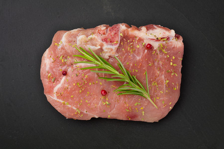 Fresh Raw Meat with Rosemary and other Spices on gray stone plate.の写真素材