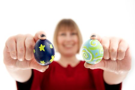 A woman holds two hand painted Easter Eggs close to the camera.    Differential focus on the eggs.の写真素材