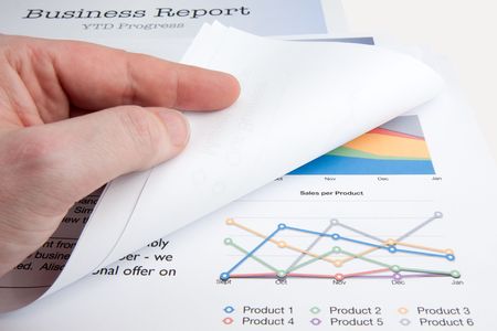 A male hand turns over a page whilst reviewing a sales report.