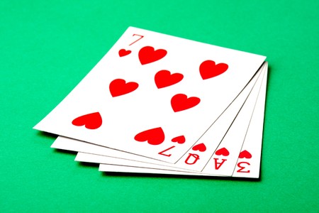 A set of four hearts playing cards that spell the word LOVE.