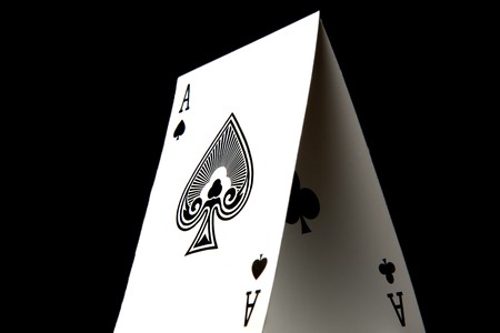 The ace of spades stacked with the ace of clubs.  Low-key on a black background.の写真素材