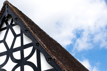 An abstract of the corner of a black and white painted roof gable.  Blue sky and clouds in the background.の写真素材