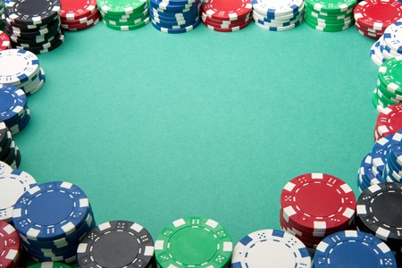 A number of gambling chips create a border on some green felt.