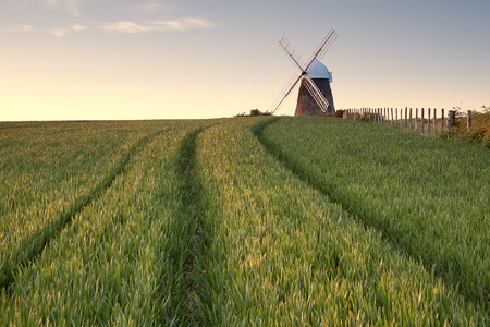 A windmill lit by the setting sun in a green field in Sussex.の写真素材