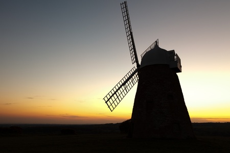 A hill top windmill silouetted against the sky after sunset.の写真素材
