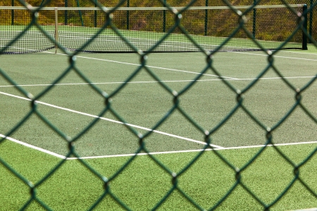 A view of an empty tennis court through the course fence.の写真素材