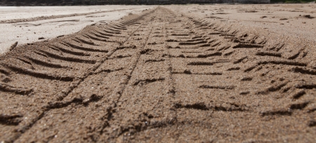 A close up of tyre treads in the soft sand of a beach at low tideの写真素材
