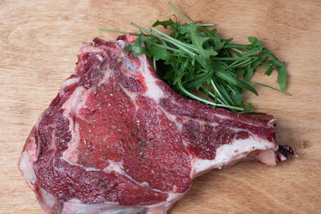 beef steak on a wooden board with greens
