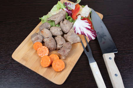 Roast pork with vegetables on a cutting board and dark backgroundの写真素材