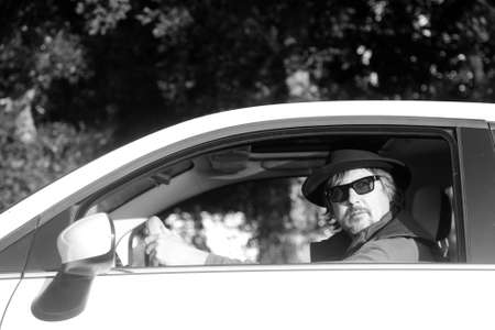man with hat and sunglasses driving a car in black and whiteの写真素材