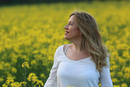 woman portrait with yellow flowers field backgroundの写真素材