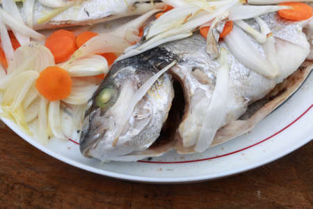 raw dorada fish with onion and carrots ready to cookの写真素材