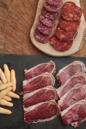 slices of salami and breadsticks on a wooden board