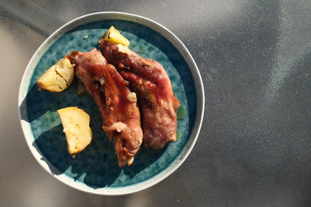 Pork ribs with potatoes on a blue plate, top view.