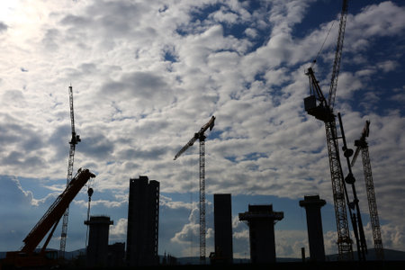 Silhouette of cranes and building under construction against blue sky belfast