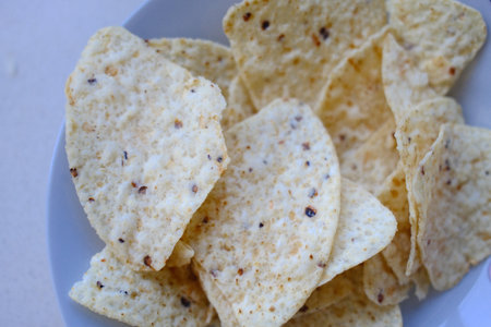 Tortilla chips in a white plate on a white background.
