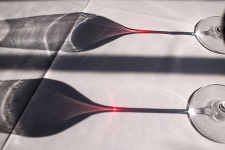 Two glasses of wine on a white tablecloth with shadow and lightの写真素材