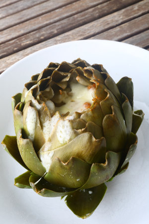 Artichoke on a white plate on a wooden table in a restaurantの写真素材