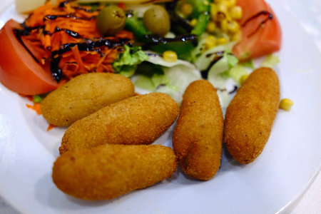 Crispy croquettes on a white plate with a saladの写真素材
