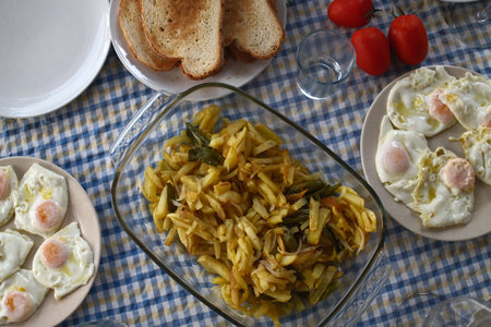Traditional breakfast with fried eggs and vegetables in a glass bowl on the table