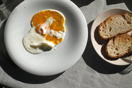 Breakfast with fried egg, bread and butter on a white plateの写真素材