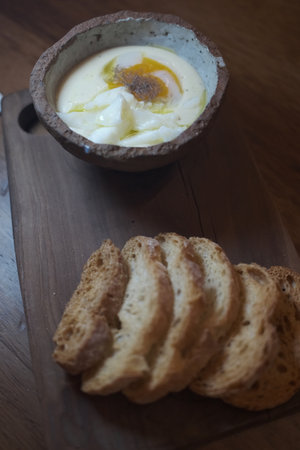 Eggs in a clay bowl with bread on a wooden table