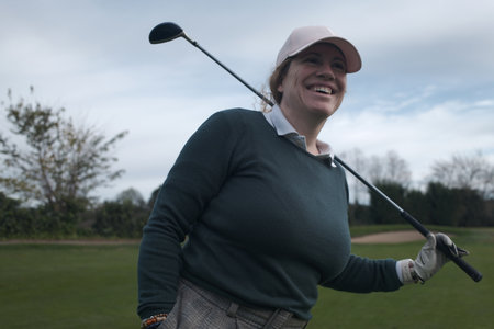 Young woman golfer with golf club and ball on golf course.の写真素材