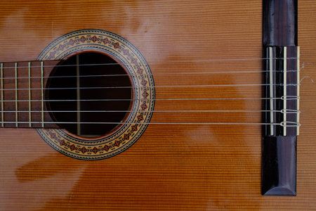 Detail of an acoustic guitar on a wooden background. Shallow depth of field