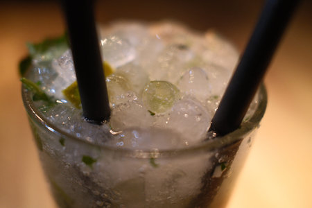 Cocktail with ice cubes and straws on a wooden table