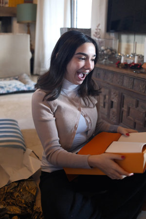 Young woman sitting on the floor at home and reading a bookの写真素材
