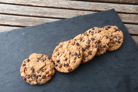 Chocolate chip cookies on slate plate, on wooden table background.