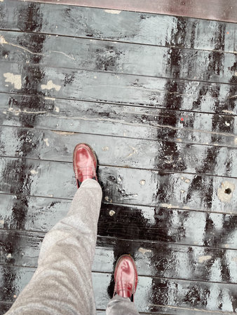 Selfie of feet in red shoes on a wooden floor with rain dropsの写真素材