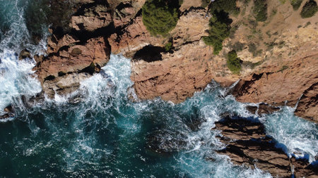 Aerial view of the ocean waves breaking on the rocky coast.