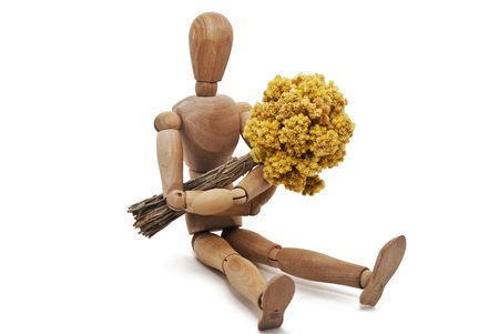 a sitting wooden mannequin with a bunch of immortelle flowersの写真素材