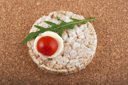 Rice cracker with tomato on a cork tableの写真素材