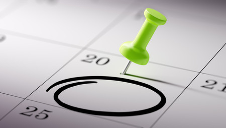 Concept image of a Calendar with a green push pin. Closeup shot of a thumbtack attached. Circle mark written on a white notebook to remind you an important appointment.の写真素材