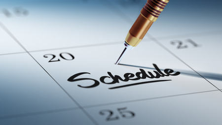 Concept image of a Calendar with a golden dart stick. The words Schedule written on a white notebook to remind you an important appointment.の写真素材