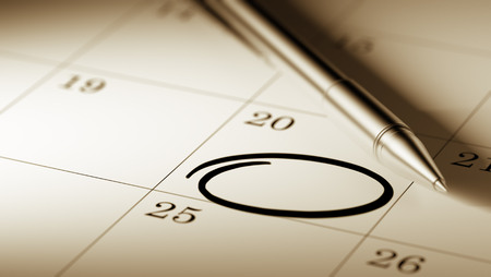 Closeup of a personal agenda setting an important date written with pen. Circle mark written on a white notebook to remind you an important appointment.の写真素材