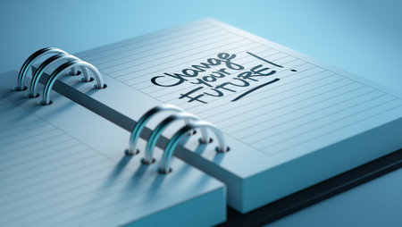 Closeup of a personal agenda setting an important date representing a time schedule. The words Change your future written on a white notebook to remind you an important appointment.の写真素材
